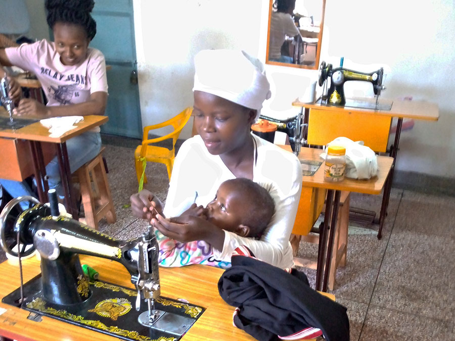Teen mother sewing with child